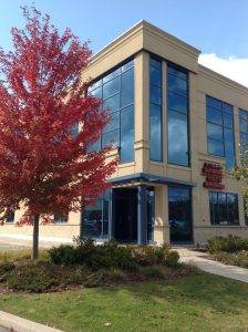 Modern building with large glass windows and a red-leaved tree in front. Modern building with large glass windows and a red-leaved tree in front.